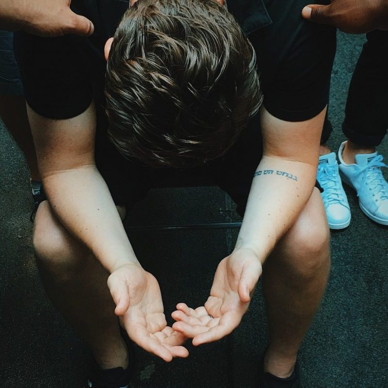 man sitting on chair holding and surrounded by people